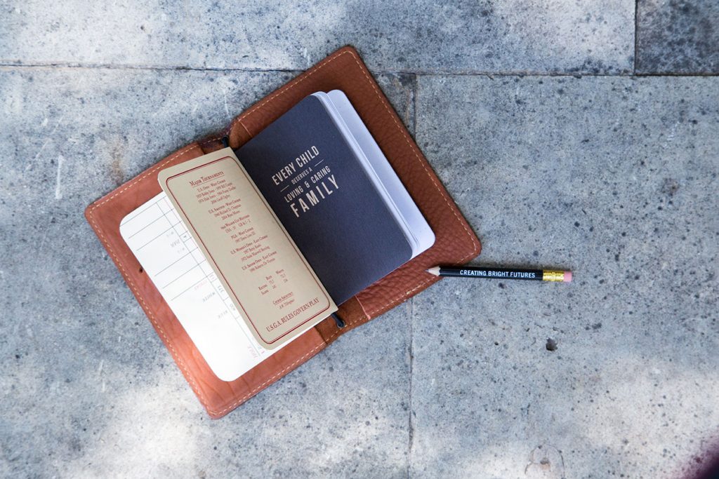 A leather portfolio mockup with a pen and pencil on the ground.