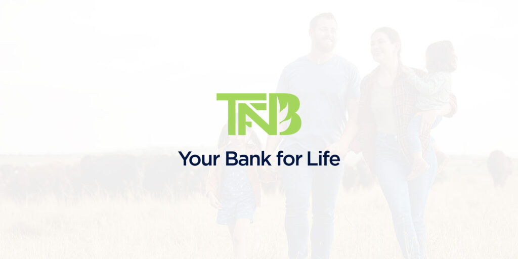 TFNB logo with the tagline "Your Bank for Life" and an Updated 2025 look, over a faded background image of a smiling family walking outdoors in a field.